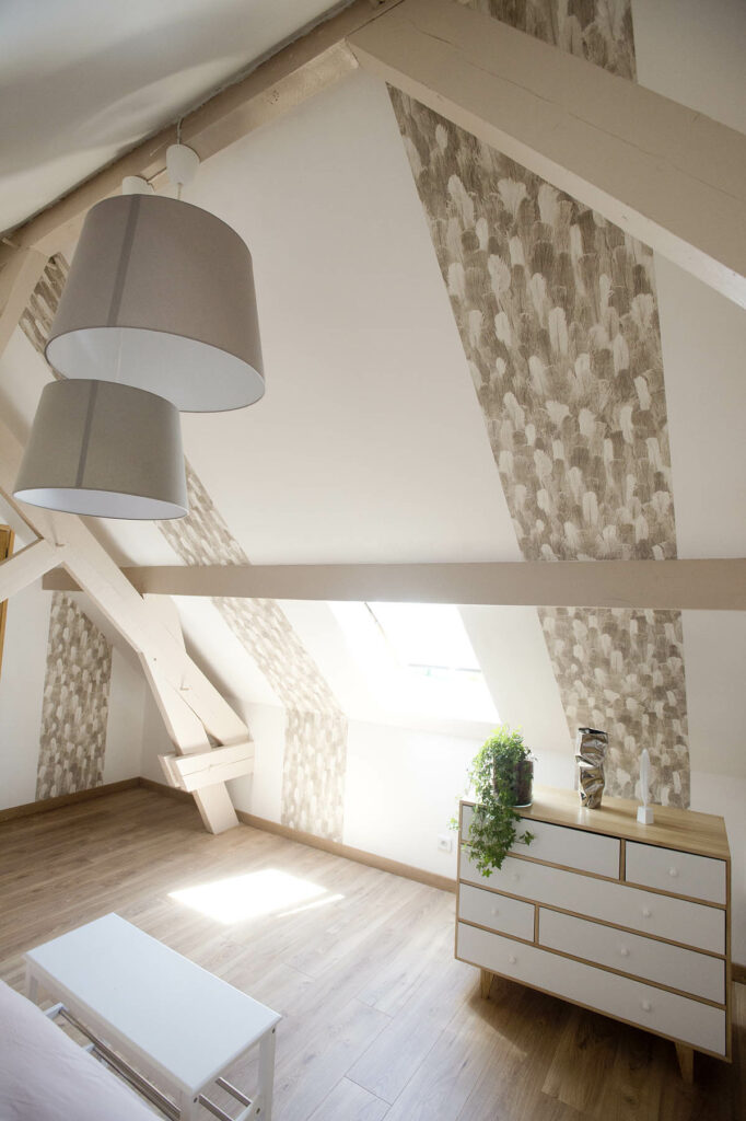 Attic room with a chandelier, exposed beams, and taupe decor.