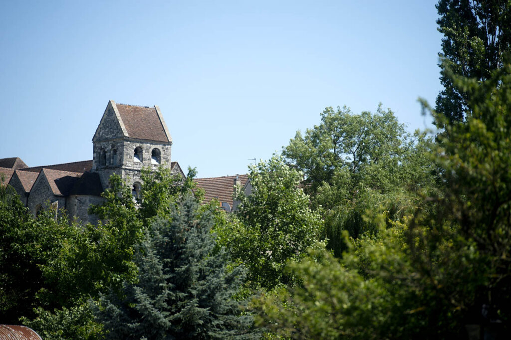 Bell tower of a church surrounded by trees under a blue sky.